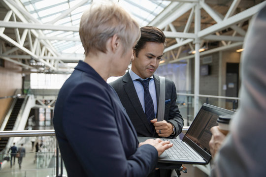 Business People Using Laptop On Office Atrium Balcony