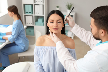 Plastic surgeon applying marks on patient's face in clinic
