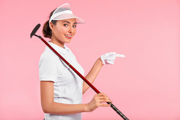 Beautiful female golfer pointing at something on color background