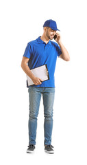 Handsome delivery man talking by phone on white background