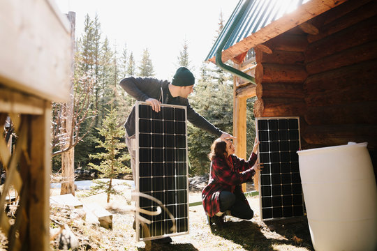 Couple installing solar panels outside cabin