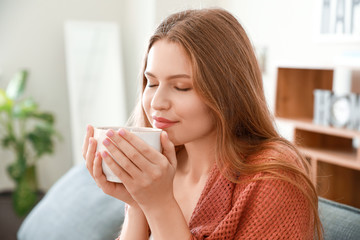 Happy woman with cup of tea resting at home