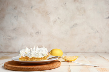 Plate with piece of tasty lemon pie on table