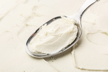 Spoon with tasty cream cheese, closeup