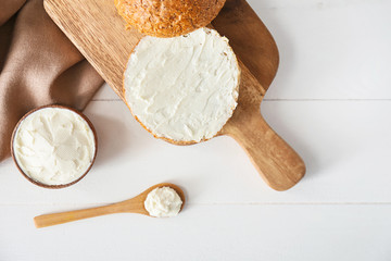 Fresh bun with tasty cream cheese on table