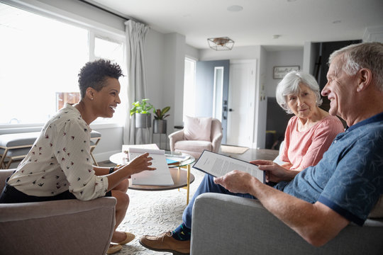 Financial advisor discussing paperwork with senior couple in living room