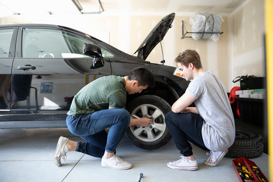 Young men changing car tire in garage