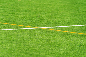 Obraz premium Green artificial grass turf soccer football field background with white and yellow line boundary. Top view