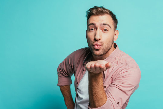 smiling handsome man blowing air kiss isolated on blue