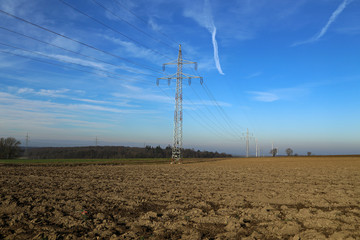 Landscape with electric pylons against the blue sky