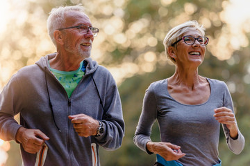 Cheerful active senior couple jogging in the park. Exercise together to stop aging.