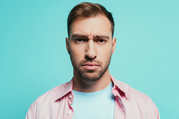 Obraz premium portrait of serious handsome man looking at camera, isolated on blue