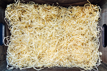 Packaging material wood shavings in a black wooden box with handles. Copy space