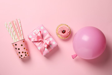 Gift box, balloon, cupcake and paper cup with straws on pink background, top view