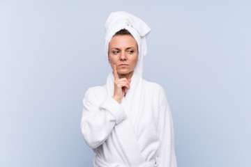 Woman in bathrobe over isolated blue background thinking an idea