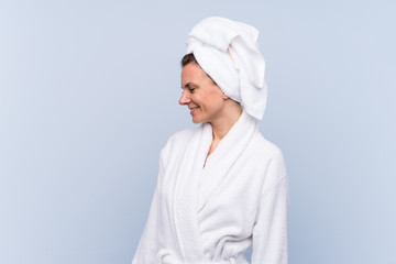 Woman in bathrobe over isolated blue background looking to the side