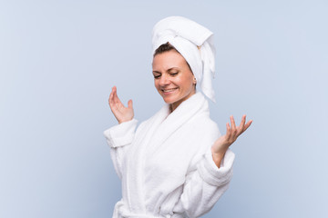 Woman in bathrobe over isolated blue background laughing