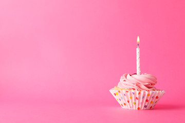 Cupcake with candle on pink background, space for text