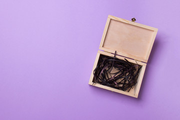open wood box with black filler lying on purple background, top view with copys pace