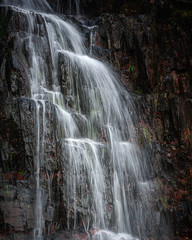 Beautiful waterfall in Scottish Highlands.Power of nature.Motion in water splashing on dark rocks.Tranquil, dark landscape scene with atmospheric mood.Cascade of flowing water. 