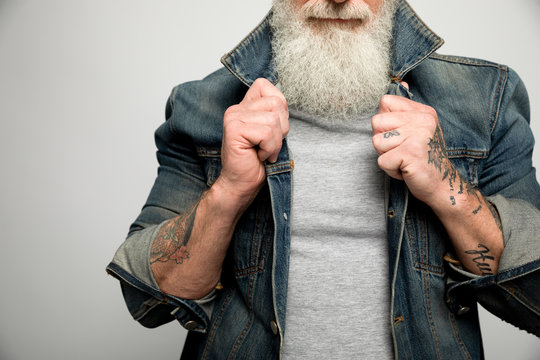 Cool man with gray beard and tattoos wearing denim jacket