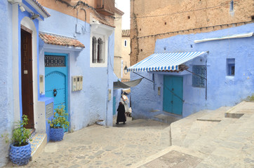 Fototapeta na wymiar An arabic woman walking toward the end of the old town at Chefchaouen old medina.
