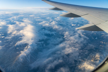 Naklejka na ściany i meble wing of airplane flying above mountains