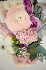 Close up of two golden wedding rings and bridal bouquet on mirror table, copy space. Selective focuse. Wedding concept
