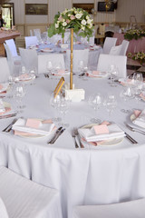 Table set with blank guest card, plate with pink and white serviette and cutlery on table, copy space. Place setting at wedding reception. Table served for wedding banquet in restaurant