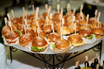Buffet table with mini hamburgers at luxury wedding reception, copy space. Serving food and appetizers at restaurant. Catering banquet table