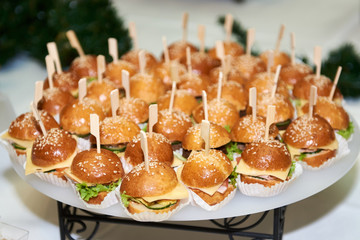 Buffet table with mini hamburgers at luxury wedding reception, copy space. Serving food and appetizers at restaurant. Catering banquet table