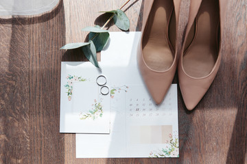 Luxury set of wedding invitations, wedding rings, elegant bride shoes on high heels on wood brown...