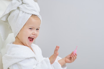 Little cute girl with a towel on her head does a manicure in her bedroom.