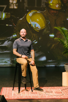 Portrait confident male firefighter with tattoos giving inspirational speech on stage