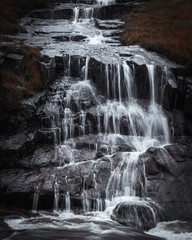 Waterfall in Scottish Highlands.Cascade of water splashing on dark rocks in Etive valley, Glencoe,Scotland, UK.Power in nature.Motion of flowing water.Tranquil landscape scene.Horizontal nature image.