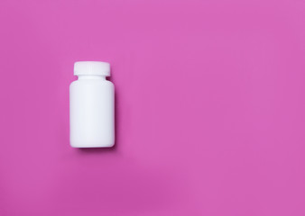 White plastic medical container for pills on purple colored paper background with copy space.