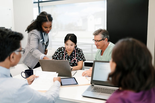 Doctors, Nurse And Administrator Meeting, Using Laptop In Clinic