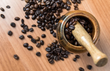 close up shot of mortar and pestle crushing coffee beans against wooden background