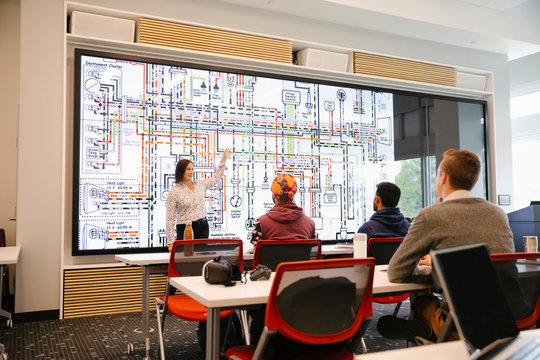 Engineering Students Listening To Teacher Explain Diagram On Whiteboard