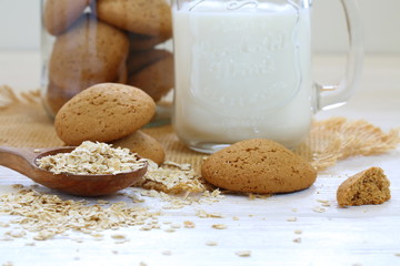 Oatmeal cookies with milk on a white wooden background