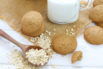 Oatmeal cookies with milk on a white wooden background