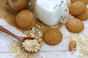 Oatmeal cookies with milk on a white wooden background