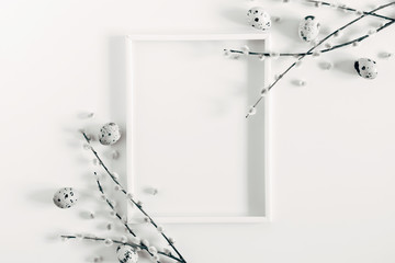 Easter holiday composition. Blank frame for text, easter eggs and willow branch on white background. Flat lay, top view, copy space