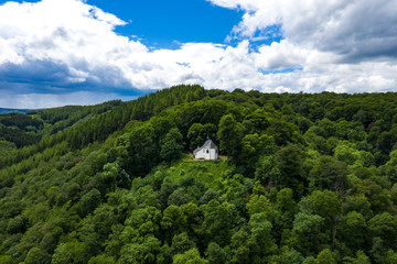 Aerial view of a little white church on a mountain in the belgium ardennes