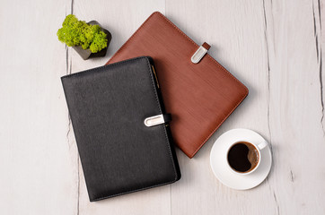 Two leather notebooks on wooden background with cup of coffe and green fresh moss. Set of diary or notebook in hard leather cover on wood table. Top view, copy space.