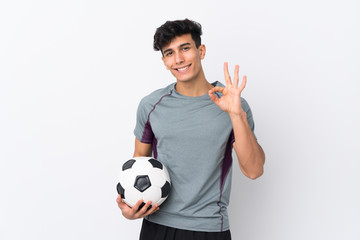 Young Argentinian man over isolated white background with soccer ball and making OK sign