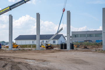 on a construction site, concrete columns for a factory building are placed with the help of a large...
