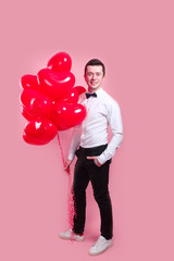 Elegant young man with heart shape air balloons on pink background. Man on Valentine's Day.