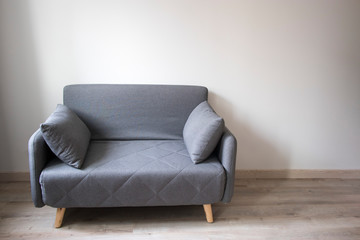 Gray sofa with pillows in the style of the sixties in the interior.