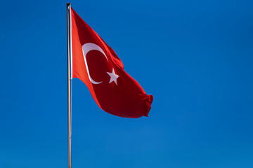 The red flag of Turkey against the blue sky the flag is developing in the wind. red rectangle with white star and white crescent.